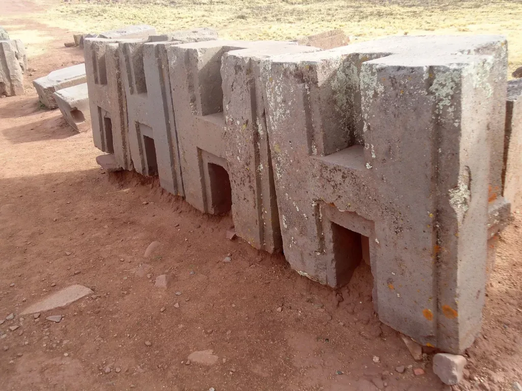 Precisely carved H-shaped andesite stone blocks at the Puma Punku archaeological site in Bolivia, showcasing advanced ancient architecture